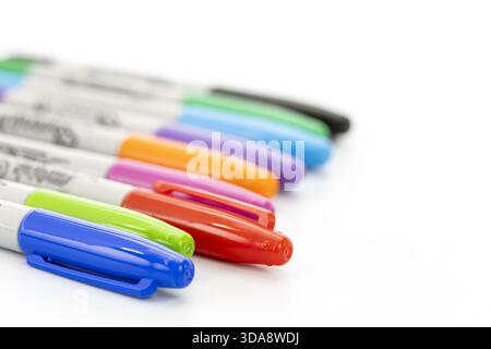A set of colorful markers with their caps on is arranged in a diagonal line on a white background, showing vibrant hues including blue, green, red, or Stock Photo
