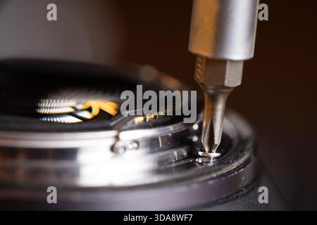 macro image of a screwdriver removing the screws form a full frame lens Stock Photo