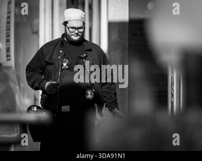 Vienna, Austria - April 7, 2020: A chimney sweeper in uniform walks along the street in springtime, captured in black and white Stock Photo