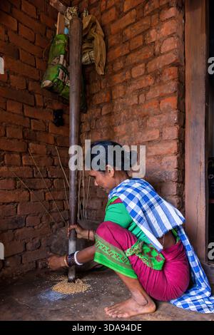 Woman during traditional rice milling with a mortar and pestle, Odisha, India Stock Photo