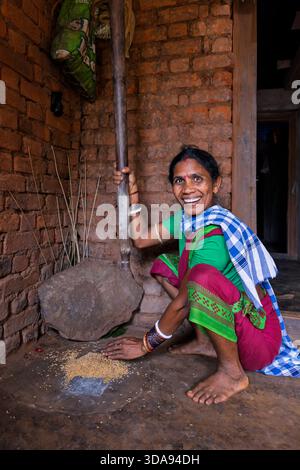 Woman during traditional rice milling with a mortar and pestle, Odisha, India Stock Photo