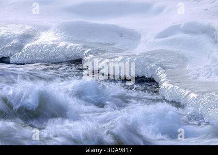Ice formation formed by frost and freezing cold temperatures over running water of stream along riverbank / river bank in winter Stock Photo