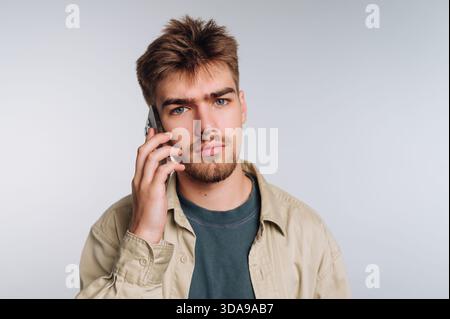 Young man with a serious expression talking on a smartphone. Stock Photo