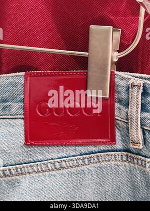 Cannes, France - 7 June 2025: Close up of a Gucci denim garment hanging in a boutique on La Croisette featuring a bright red leather logo patch clippe Stock Photo