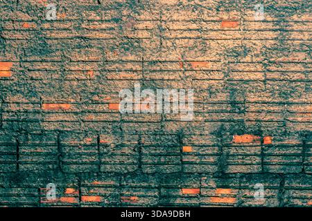 Rustic brick wall detail with weathered mortar. The earthy and greenish color palette gives the scene an aged and natural look. Grunge texture. Stock Photo