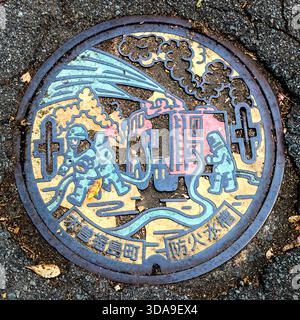 A close-up of a fire brigade manhole cover from Kiso-Fukushima, Nagano – slightly weathered and covered in patina, but the relief remains clearly legible. Kiso, Nagano Prefecture, Japan Stock Photo