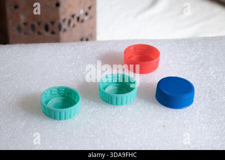 four plastic bottle caps on a bumpy white surface in the foreground Stock Photo