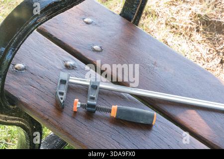 f-clamp tool in foreground center on a dark wooden bench Stock Photo