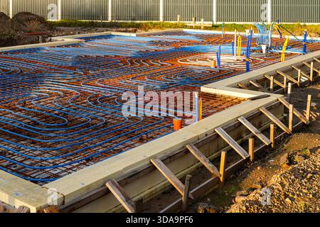 Network of underfloor heating pipes arranged on reinforced foundation, prepared for concrete pouring during modern energy-efficient home construction Stock Photo