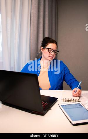 Young entrepreneur developing startup business plan at home. Determined woman working on financial projections. Innovation, business planning, and bus Stock Photo