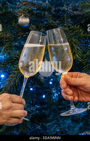 A close up of two unrecognisable people holding glasses together in a toast, with a shallow depth of field Stock Photo