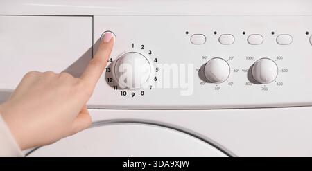 Woman pressing button on washing machine, closeup Stock Photo