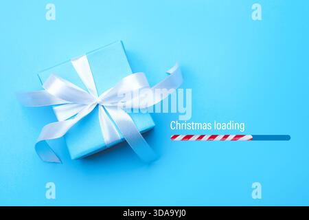 Christmas expectation. Candy cane as loading bar. Gift box on light blue background, top view Stock Photo