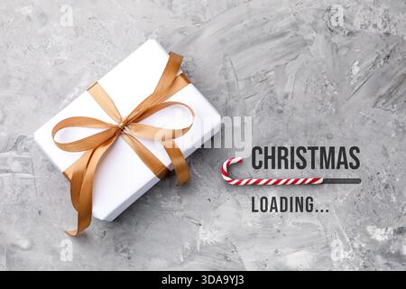 Christmas expectation. Candy cane as loading bar. Gift box on grey textured background, top view Stock Photo