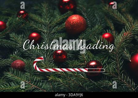 Christmas expectation. Candy cane as loading bar. Fir tree branches with red festive balls, closeup Stock Photo