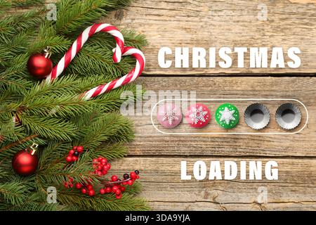Christmas loading, holiday expectation. Fir tree branches with red festive balls and candy canes on wooden background, top view Stock Photo