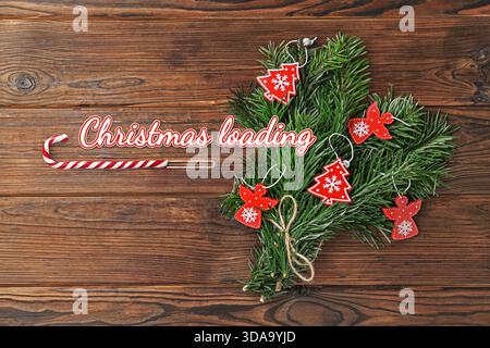 Christmas expectation. Candy cane as loading bar. Fir tree branches with festive decor on wooden background, top view Stock Photo