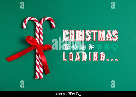 Christmas expectation. Snowflakes as loading bar. Candy canes with red bow on green background, top view Stock Photo