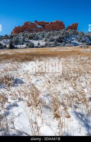 Open grass fields covered with snow with red rock formations on Bretag Trail iat Garden of the Gods Park in Colorado Springs, Colorado.. Stock Photo