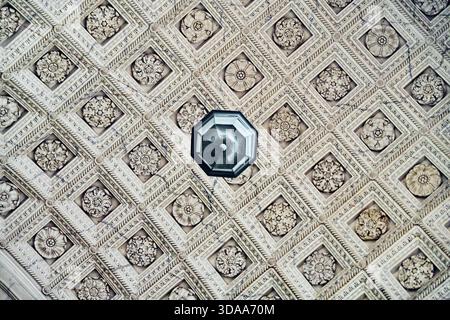 Elegant ceiling features repetitive pattern of detailed floral rosettes within square coffers. Soft natural lighting highlights elaborate textures and Stock Photo