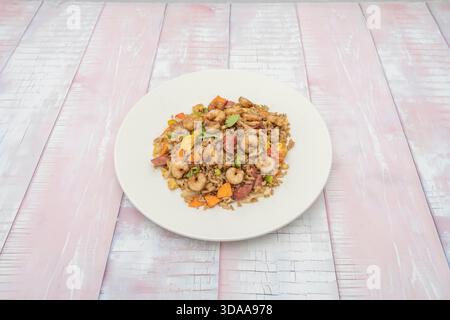 Special fried rice with whole prawns, strips of tenderloin, quail egg, and toasted cashews, presented on a platter for festive occasions Stock Photo
