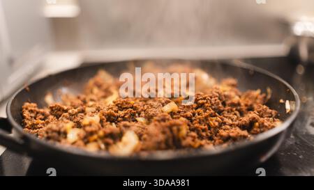 Ground beef cooking with onions in a skillet, beautifully presented. Sizzling, savory, and ready for tacos, pasta, or rice dishes. Homestyle cooking Stock Photo