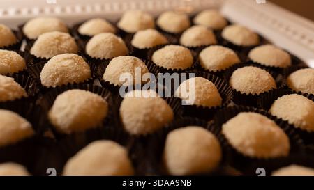 Beautiful beijinhos arranged on a plate, coated in shredded coconut. Traditional Brazilian coconut sweet, perfect for parties, desserts, and cultural Stock Photo