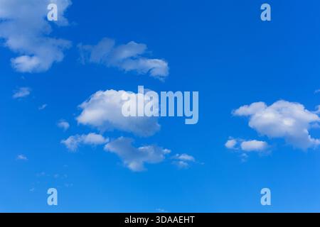 White clouds scattered across a bright blue sky Stock Photo