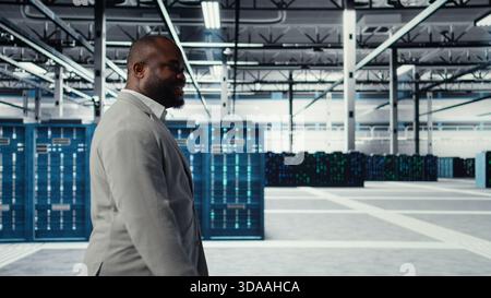 Engineer walking in data center facility, doing inspection on hardware tech handling user requests. Employee in server farm analyzing traffic patterns of supercomputers, camera A Stock Photo