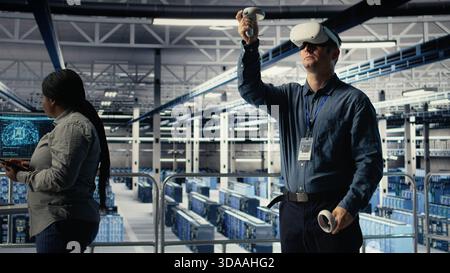 Server farm programmer uses VR headset to install updates and keep AI systems running. Data center employee uses virtual reality tech to write code improving infrastructure output, camera A Stock Photo