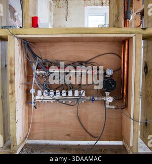 Underfloor heating manifold system with thermostatic valves and copper piping installed during building renovation work Stock Photo