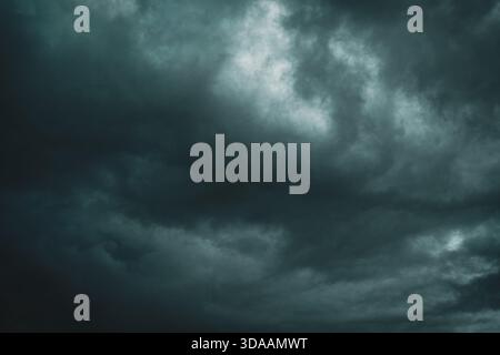 A dark and dramatic storm sky with heavy, swirling clouds creating an intense and moody atmosphere Stock Photo