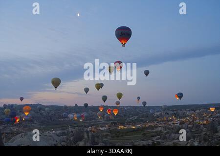 Many hot air balloons float at dusk over the picturesque landscape of Cappadocia, Goereme National Park, Goereme Tarihi Milli ParkIJ, Nevsehir Provi Stock Photo