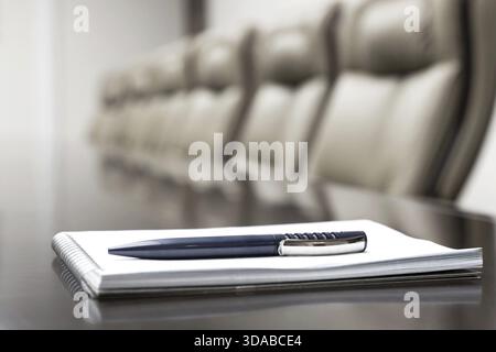 Closeup of notepad kept on table in empty conference room Stock Photo