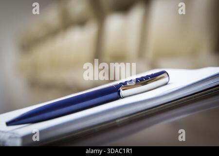 Closeup of notepad kept on table in empty conference room Stock Photo