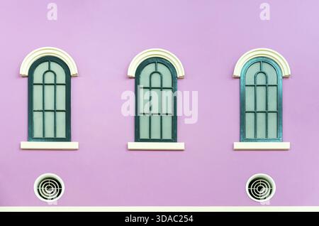 Three green arched windows on pink wall of the house in Italy retro style Stock Photo