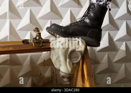 Black army boots standing on gas mask in an abandoned basement Stock Photo