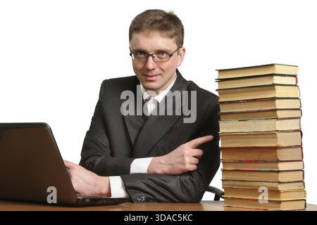 Young guy working at a laptop and shrugs off paper books isolated on white background Stock Photo
