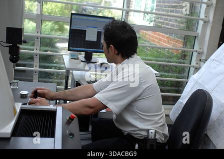 Workers guiding a computed guided lathe in an engineering factory. Stock Photo