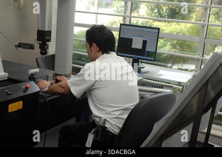 Workers guiding a computed guided lathe in an engineering factory. Stock Photo