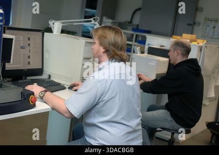 Workers guiding a computed guided lathe in an engineering factory. Stock Photo