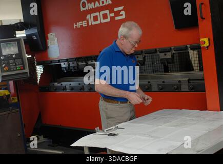 Workers guiding a computed guided lathe in an engineering factory. Stock Photo