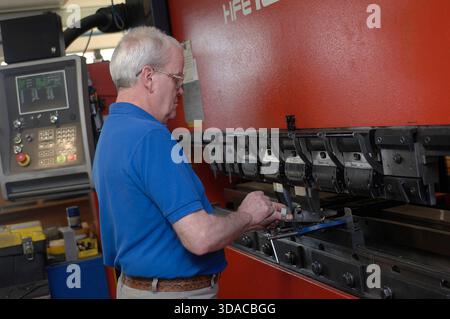 Workers guiding a computed guided lathe in an engineering factory. Stock Photo