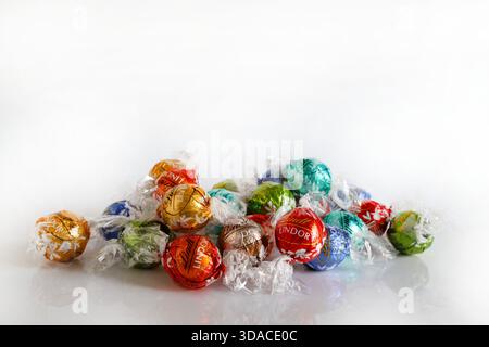 Florence, Italy, December 8, 2025. Lindt Lindor Swiss chocolates truffles assorted flavours on a white background. Colourfully wrapped chocolates. Stock Photo