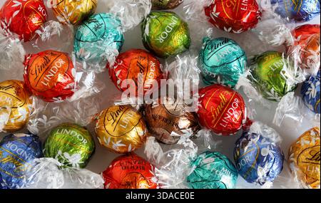 Florence, Italy, December 8, 2025. Lindt Lindor Swiss chocolates truffles assorted flavours background. Colourfully wrapped chocolates. Overhead view. Stock Photo