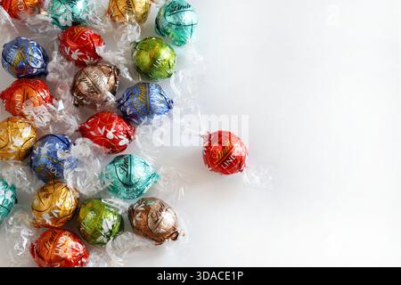 Florence, Italy, December 8, 2025. Lindt Lindor Swiss chocolates truffles assorted flavours on a white background. Colourfully wrapped chocolates. Stock Photo