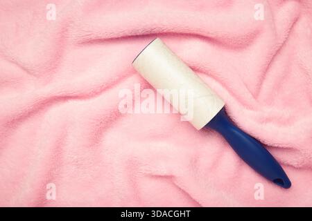 Lint roller on pink texture background to remove pet animal hair. Top view Stock Photo