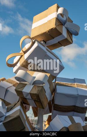 Pile of wrapped Christmas presents with ribbons tied around them in a seasonal display of gifts at Gunwharf quays, Portsmouth harbour, Hampshire, UK Stock Photo