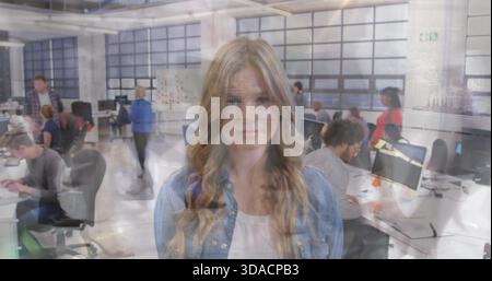 Young woman in modern office, colleagues working on computers in background Stock Photo