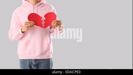Young man with broken paper heart on grey background with space for text Stock Photo